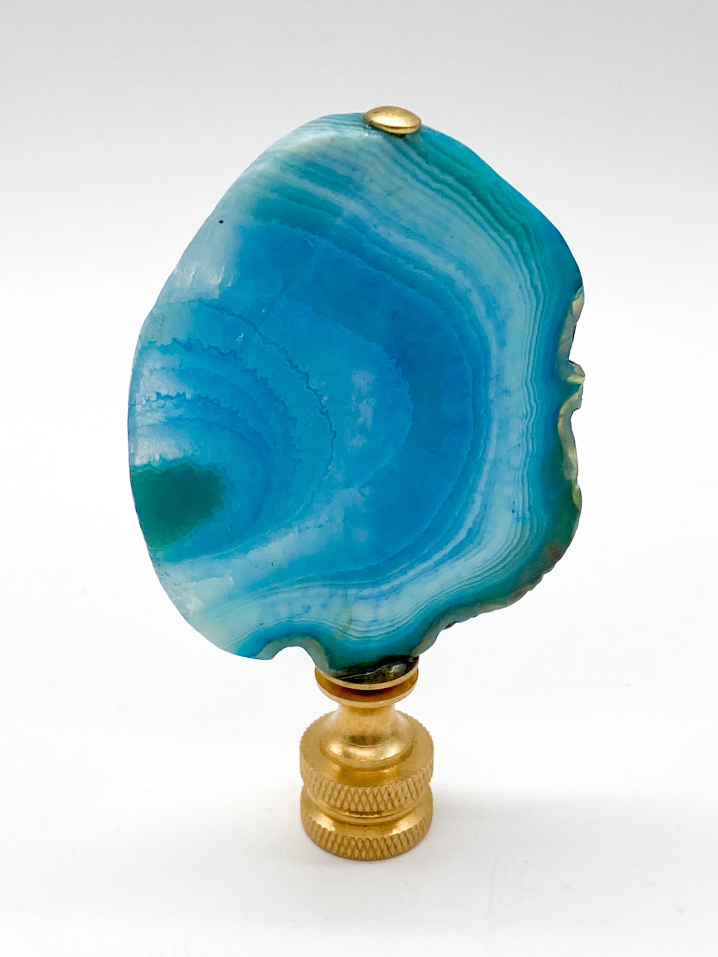 Blue agate mineral lamp finial with natural banding and translucent crystal patterns on a knurled brass fitting
