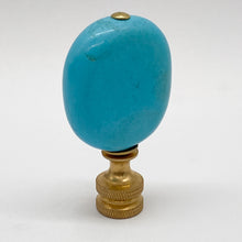Load image into Gallery viewer, A vintage-style decorative object featuring a smooth, rounded turquoise-blue stone or cabochon mounted on a textured brass or gold-toned metal base, set against a plain light gray background.